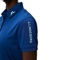 Nahaufnahme eines blauen Polohemds der Marke J. Lindeberg mit weißem Logo-Detail