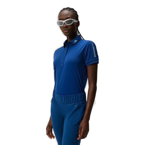 Sportliche Frau in blauem J.Lindeberg Poloshirt und Hose mit Sonnenbrille