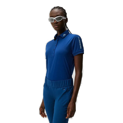 Sportliche Frau in blauer J.Lindeberg Sportbekleidung mit weißer Sonnenbrille