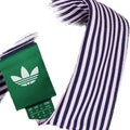 Nahaufnahme eines Adidas-Hemdes mit dunkelblau-weißem Streifenmuster, grünem Etikett mit Adidas-Trefoil-Logo und schwarzen Knöpfen