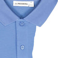 Nahaufnahme eines hellblauen J.Lindeberg Poloshirts mit Fokus auf den Kragen, die Knöpfe und das subtile Logo-Stickerei
