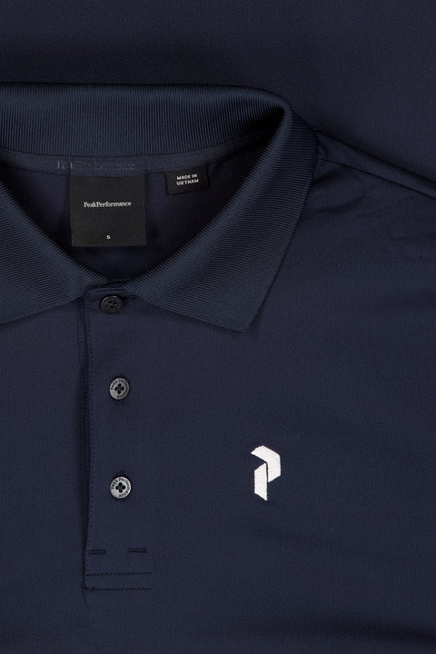 Detailaufnahme eines dunkelblau Peak Performance Poloshirts mit weißem Logo, Kragen und Knöpfen, Größe S, Made in Vietnam
