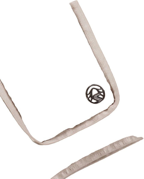 Nahaufnahme einer beigen Pufferjacke mit gestepptem Muster, zeigt eine Tasche mit grauem Rand und einem runden Logo-Button, sowie Nähte und Texturdetails des Materials