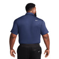 Rückansicht eines Mannes in einem marineblauen Nike Poloshirt und schwarzer Hose