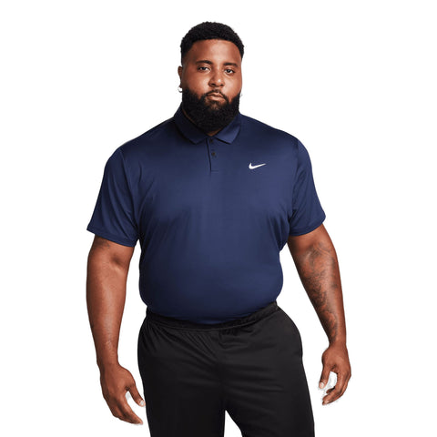 Ein muskulöser Mann trägt ein marineblaues Nike Poloshirt und schwarze Hose