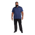 Ein Plus-Size-Modell trägt ein blaues Nike Poloshirt und schwarze Hose