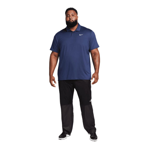Ein Plus-Size-Modell trägt ein blaues Nike Poloshirt und schwarze Hose