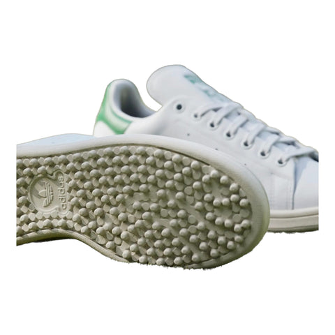 Weißer Adidas Sneaker mit strukturierter Sohle auf grünem Rasen